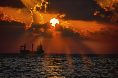 Silhouette boat in calm sea at sunset