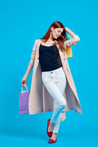 Full length of young woman against blue background