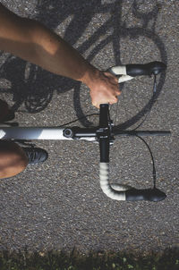 Low section of man with bicycle standing on road