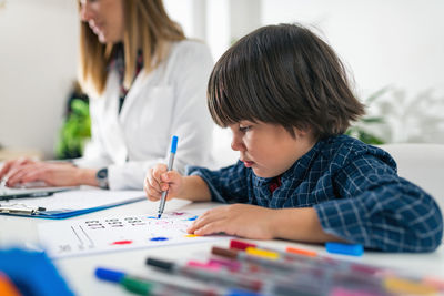 Teacher and student drawing on table in classroom