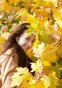 Portrait of woman standing by trees in park during autumn