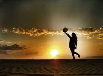 Silhouette of man standing on beach at sunset