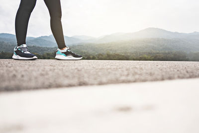 Low section of woman standing on road against clear sky