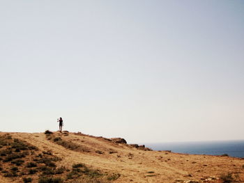 Men standing on shore by sea against clear sky