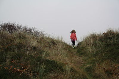 Teenage girl walking on land against sky