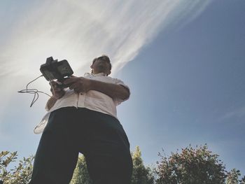 Low angle view of man photographing against sky