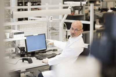 Side view of male engineer pointing at computer in manufacturing industry