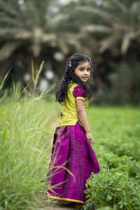 Young woman standing against plants