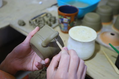 High angle view of hand holding ice cream pottery teapot clay ornament handmade