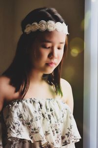 Close-up of girl wearing flowers while standing indoors