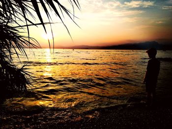 Silhouette person looking at sea against sky during sunset