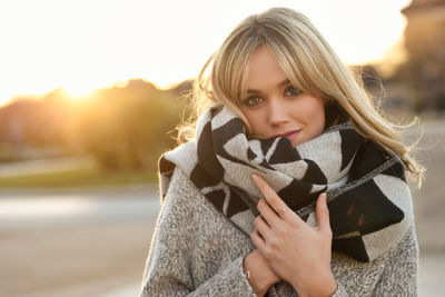 Portrait of young woman wearing warm clothing during sunset