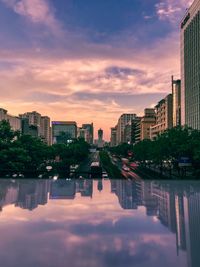 Canal amidst buildings against sky at sunset