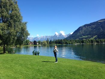 Woman standing on grassy field against lake