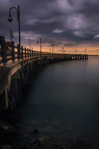 Pier over sea against sky at sunset