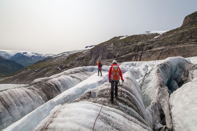 Rear view of people walking on mountain against sky