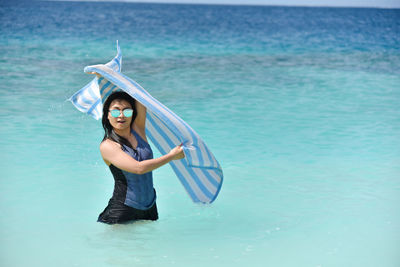 Portrait of young woman standing in sea against sky