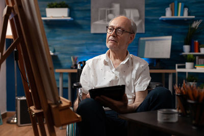 Senior man with tablet pc sitting in wheelchair