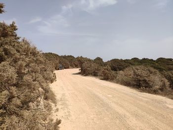 Dirt road along landscape and against sky