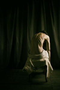 Woman from behind sitting on a stool covered with goatskin iv