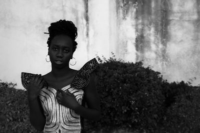 Portrait of young woman standing against trees