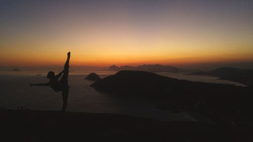 Silhouette person on beach against sky during sunset