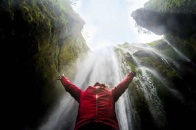 Woman standing by waterfall in forest