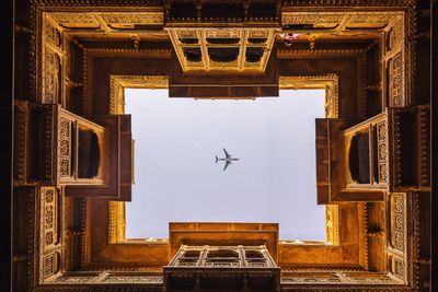 Directly below shot of airplane flying over palace in sky