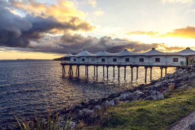 Built structure on beach against sky during sunset