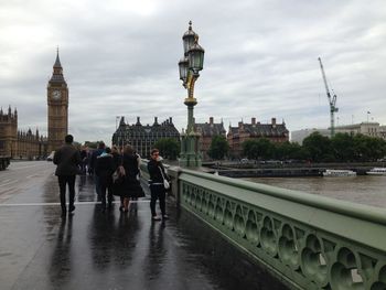 People walking on wet bridge in city during rainy season