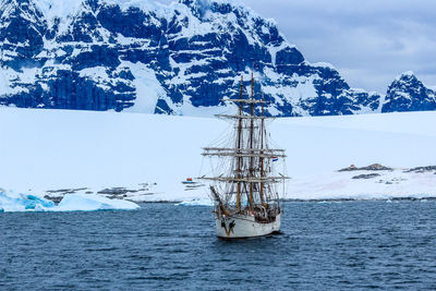 Scenic view of sea by snowcapped mountain against sky