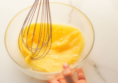 Close-up of hand stirring egg in bowl