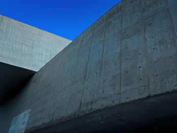 Low angle view of concrete wall against clear blue sky