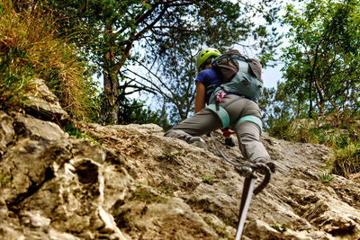 Low angle view of woman climbing cliff