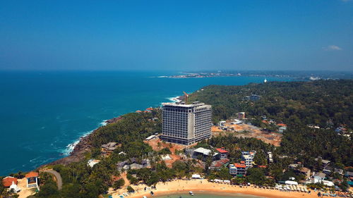 High angle view of buildings and sea against blue sky