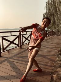 Full length of woman dancing by railing over sea against sky