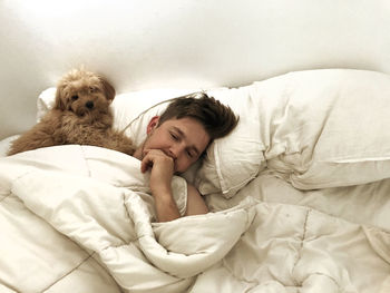 Young woman with dog resting on bed at home