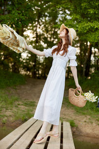 Full length of woman with arms outstretched standing on boardwalk