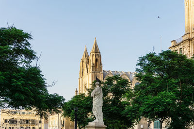 Low angle view of church and statue against sky