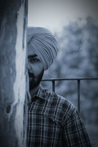 Cropped portrait of man wearing turban while standing behind wall