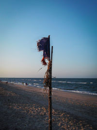 Wooden posts on beach against clear sky