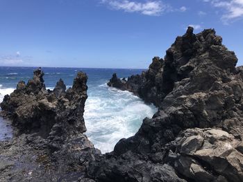 Rock formation on sea shore against sky