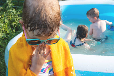 Girl after the pool stands in a towel and adjusts her sunglasses. the child makes a face