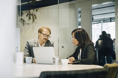 Male and female colleagues discussing while sitting in office