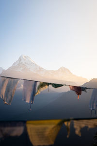 Reflection of snowcapped mountains in lake against clear sky