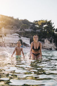 Mother and son playing with water on the sea