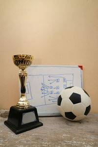 Close-up of soccer ball with award and whiteboard on table