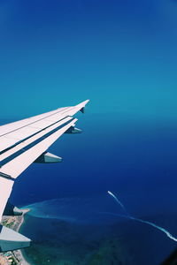 Airplane flying over sea against blue sky