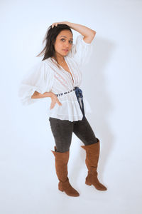 Portrait of young woman standing against white background