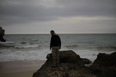 Man standing at beach against sky